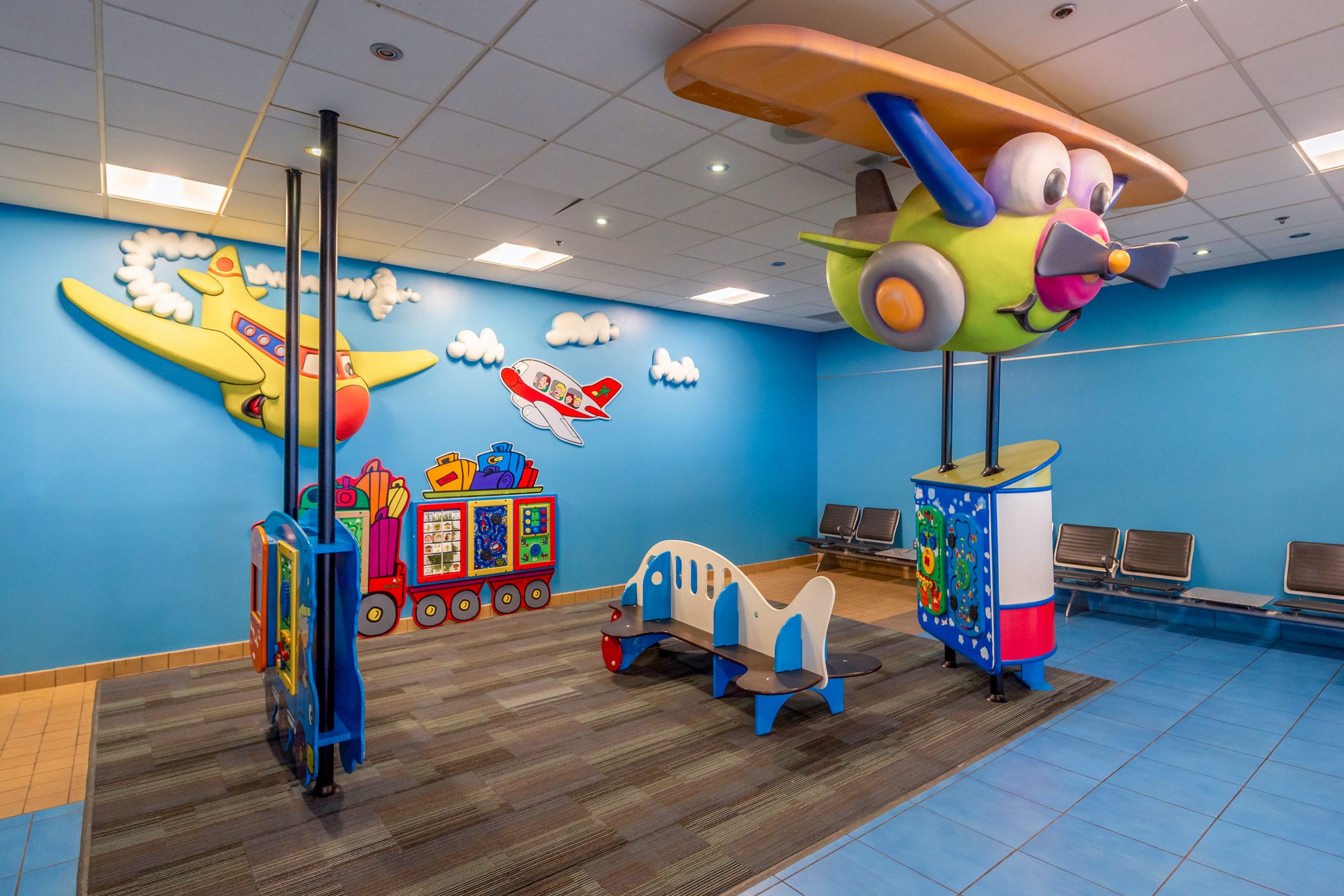 Une aire de jeux pour enfants à l'aéroport, avec des équipements colorés sur le thème de l'aviation.